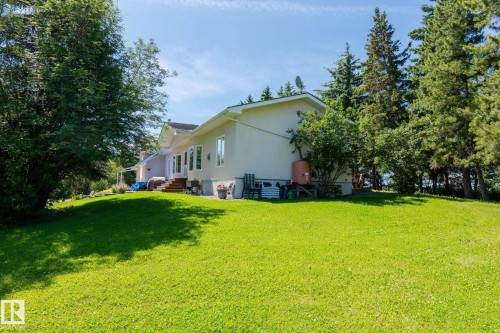Spacious backyard featuring extensive green lawn, mature trees, and a light-colored stucco exterior - 860 41 Avenue, Edmonton, AB 