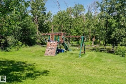 Expansive lawn area featuring a wooden playset with a climbing wall, slide, and swing set - 860 41 Avenue, Edmonton, AB 
