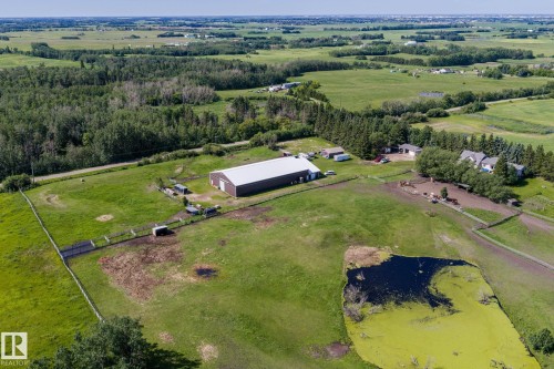 Expansive property featuring a large metal-clad barn with a light-colored roof, multiple fenced paddocks, and a visible pond - 860 41 Avenue, Edmonton, AB 