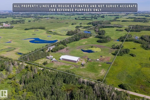 Expansive rural property featuring multiple natural ponds, a large agricultural building with a light-colored roof, and additional outbuildings - 860 41 Avenue, Edmonton, AB 
