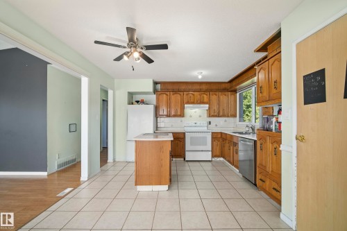 Kitchen featuring warm wood cabinetry, white appliances, a center island with countertop, and ceramic tile flooring - 14916 114A Street, Edmonton, AB 