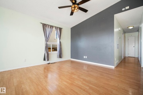 Spacious room featuring wood-finish flooring and a ceiling fan with integrated lighting - 14916 114A Street Nw, Edmonton, AB - Indoor Photo Showing Other Room
