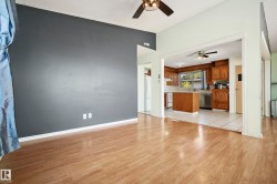 Wood-finish flooring throughout the main living area, featuring a dark accent wall and a ceiling fan - 