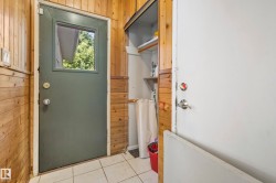 Wood-paneled room featuring a glazed door, white tile flooring, and a built-in storage alcove with shelving - 
