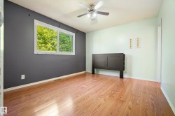 Spacious room featuring wood-finish flooring and a ceiling fan - 