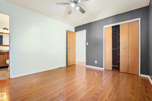 Bedroom featuring wood-finish flooring, a ceiling fan with integrated lighting, and a bi-fold door closet with shelving - 14916 114A Street, Edmonton, AB 