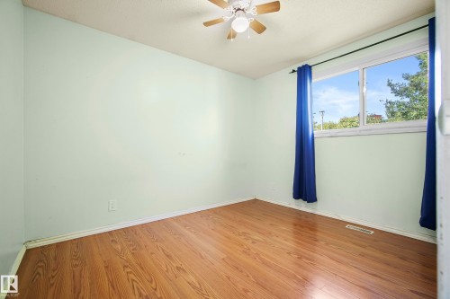 Bright room featuring wood-finish flooring, light green walls, and a ceiling fan - 14916 114A Street, Edmonton, AB 