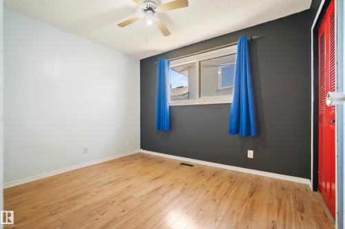 Room featuring wood-finish flooring, a ceiling fan with integrated lighting, and a window with a sill - 14916 114A Street, Edmonton, AB 