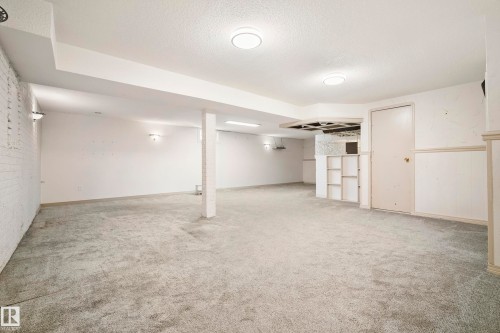 Spacious lower-level room featuring light gray carpeting, recessed ceiling lighting, and a partially finished built-in bar area with shelving - 14916 114A Street, Edmonton, AB 