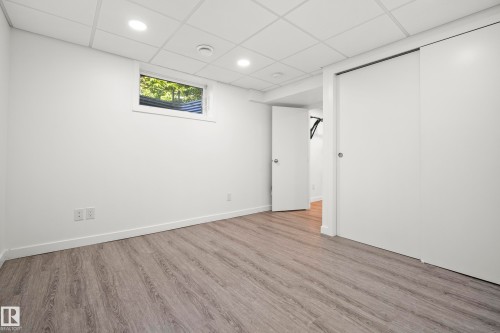 Spacious room featuring wood-finish flooring, white walls, and a drop ceiling with recessed lighting - 14916 114A Street, Edmonton, AB 