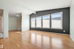 Bright room featuring wood-finish flooring, a vaulted ceiling, and four large windows with white blinds - 