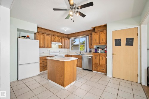 Kitchen featuring extensive wood cabinetry, a central island with a solid surface countertop, and large format tile flooring - 14916 114A Street, Edmonton, AB 
