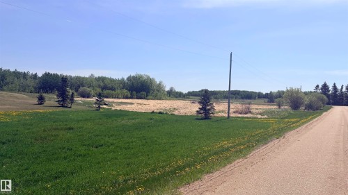 Expansive rural landscape featuring a gravel road, open fields, and distant tree lines - 458 20212 Twp Road 510, Rural Strathcona County, AB 
