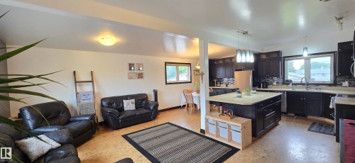 Open-concept living space featuring wood-finish flooring, a kitchen island with storage, dark wood cabinetry, a tiled backsplash, and recessed lighting - 5304 49 Street, Two Hills, AB - Indoor Photo Showing Living Room
