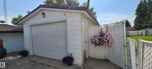 Detached garage with horizontal siding, a roll-up garage door, and a side access door - 5304 49 Street, Two Hills, AB - Outdoor With Exterior