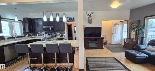 Spacious kitchen with dark wood cabinetry, stainless steel appliances, and a large island with seating - 5304 49 Street, Two Hills, AB - Indoor