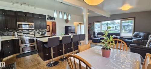 Spacious kitchen featuring dark wood-finish cabinetry, stainless steel appliances, and a central island with countertop seating - 5304 49 Street, Two Hills, AB - Indoor