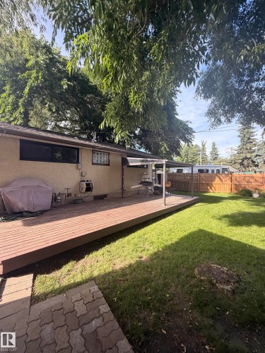 Expansive backyard featuring a wood-finish deck, covered patio area, and mature trees - 8 Savoy Place, St. Albert, AB 