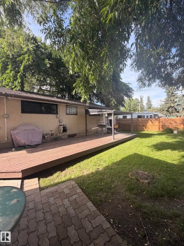Expansive backyard featuring a wood-finish deck, a covered patio area, and a green lawn - 8 Savoy Place, St. Albert, AB 