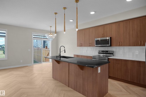Open-concept kitchen and dining area featuring wood-finish herringbone flooring - 8523 Mayday Run, Edmonton, AB 