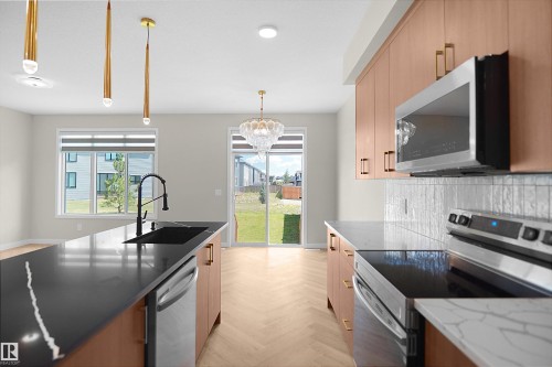 Kitchen featuring a center island with a black sink and stainless steel dishwasher - 8523 Mayday Run, Edmonton, AB 