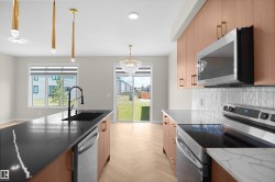 Kitchen featuring a center island with a black sink and stainless steel dishwasher - 