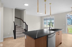 Kitchen island with a dark countertop and integrated sink, stainless steel dishwasher, and wood-finish cabinetry - 