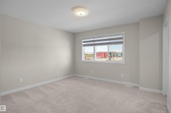 Carpeted room featuring a large window with horizontal blinds, neutral wall paint, and white trim - 