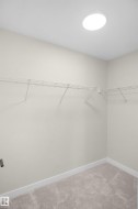 Walk-in closet featuring light-toned walls, white wire shelving, recessed ceiling lighting, and plush carpet flooring - 