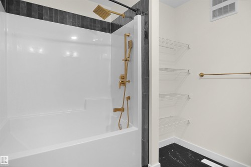 Shower and tub combination featuring a gold-toned rain shower head and handheld sprayer - 8523 Mayday Run, Edmonton, AB 