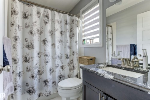 Bathroom featuring a dark wood-finish vanity with a white-veined countertop, an undermount sink, a chrome-finish faucet, and a large wall-mounted mirror - 1311 30 Avenue, Edmonton, AB 