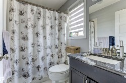 Bathroom featuring a dark wood-finish vanity with a white-veined countertop, an undermount sink, a chrome-finish faucet, and a large wall-mounted mirror - 