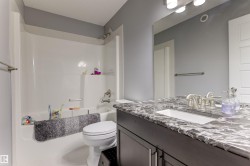 Bathroom featuring a dark wood-finish vanity with an undermount sink, a stone-finish countertop, and a brushed nickel faucet - 
