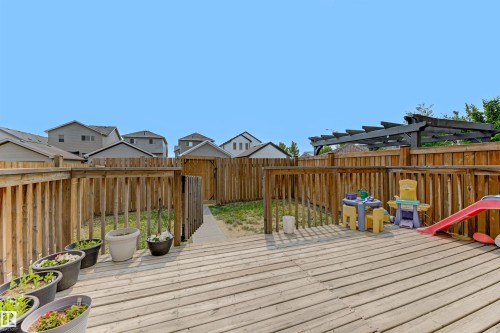 Rear yard featuring a spacious wood deck, wood privacy fencing, and a dark-stained wood pergola - 1311 30 Avenue, Edmonton, AB 