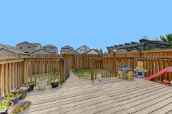 Rear yard featuring a spacious wood deck, wood privacy fencing, and a dark-stained wood pergola - 