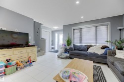 Spacious living area featuring light gray walls and white tile flooring - 