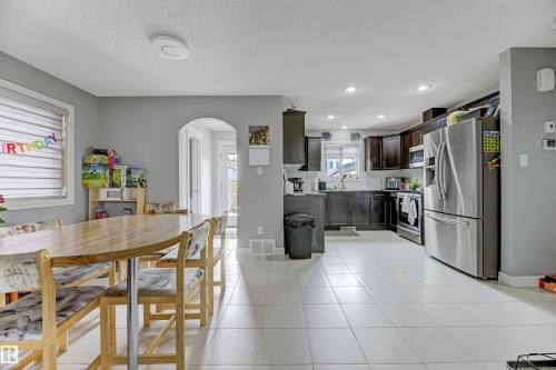 Open-concept living space with light-toned tile flooring, recessed lighting, and an arched doorway - 1311 30 Avenue, Edmonton, AB 