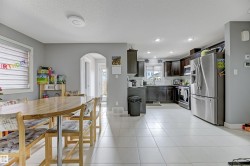 Open-concept living space with light-toned tile flooring, recessed lighting, and an arched doorway - 