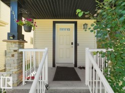 Cream-colored siding exterior featuring a multi-paneled entry door with three upper window lites and dark trim - 