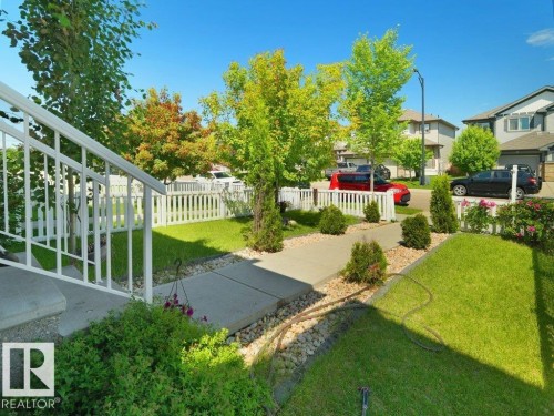 Front yard featuring a concrete walkway, white picket fence, and mature landscaping - 1419 27 Av, Edmonton, AB 