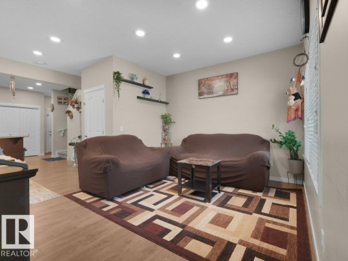 Recessed lighting illuminates this living area featuring wood-finish flooring and light-toned wall paint - 1419 27 Av, Edmonton, AB 