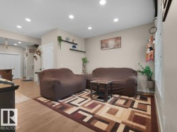 Recessed lighting illuminates this living area featuring wood-finish flooring and light-toned wall paint - 