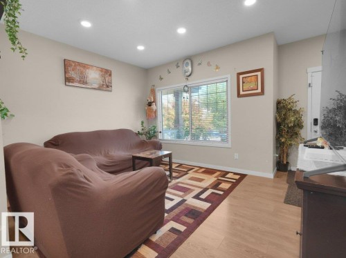 Living area with light wood-finish flooring, recessed ceiling lighting, and neutral wall tones - 1419 27 Av, Edmonton, AB 