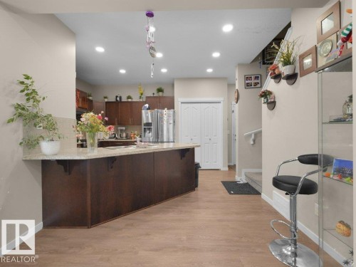 Kitchen featuring a large central island with seating, wood-finish flooring, recessed lighting, and a neutral color palette - 1419 27 Av, Edmonton, AB 