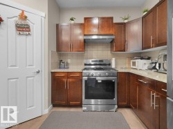 Kitchen featuring wood-finish cabinetry, stainless steel range and hood, light-toned countertops, and a tiled backsplash - 