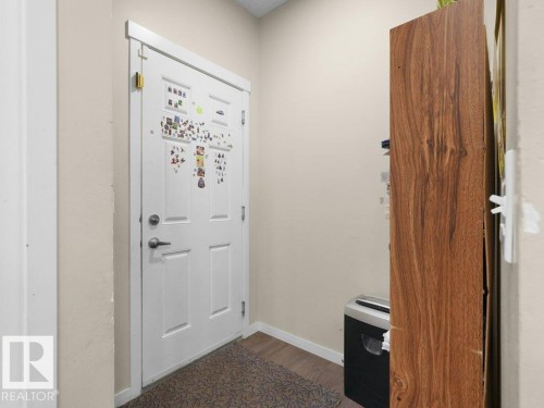 White paneled door with brushed nickel hardware, complemented by light neutral wall paint and wood-finish flooring - 1419 27 Av, Edmonton, AB 
