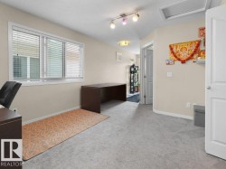 Neutral-toned room featuring light gray carpeting, a multi-pane window with blinds, and a white interior door - 