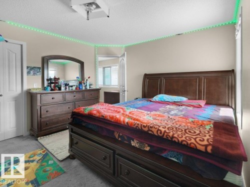 Interior room featuring neutral wall paint, carpet flooring, a white paneled door, and a textured ceiling - 1419 27 Av, Edmonton, AB 