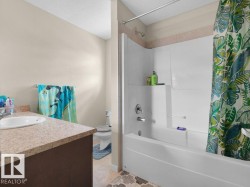 White bathtub and shower combination unit featuring a built-in shelf and chrome fixtures, complemented by a light-toned wall tile accent - 