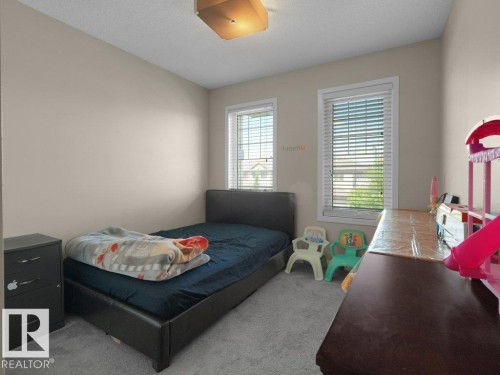 Carpeted interior room with neutral-toned walls, two windows featuring white blinds, and a flush mount ceiling light fixture - 1419 27 Av, Edmonton, AB 